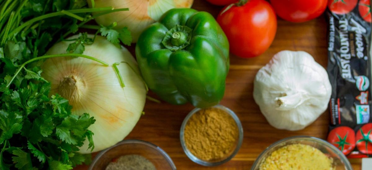 An assortment of fresh vegetables and spices on a wooden table for healthy cooking.