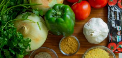 An assortment of fresh vegetables and spices on a wooden table for healthy cooking.