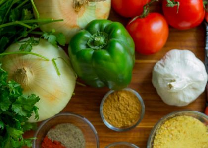 An assortment of fresh vegetables and spices on a wooden table for healthy cooking.