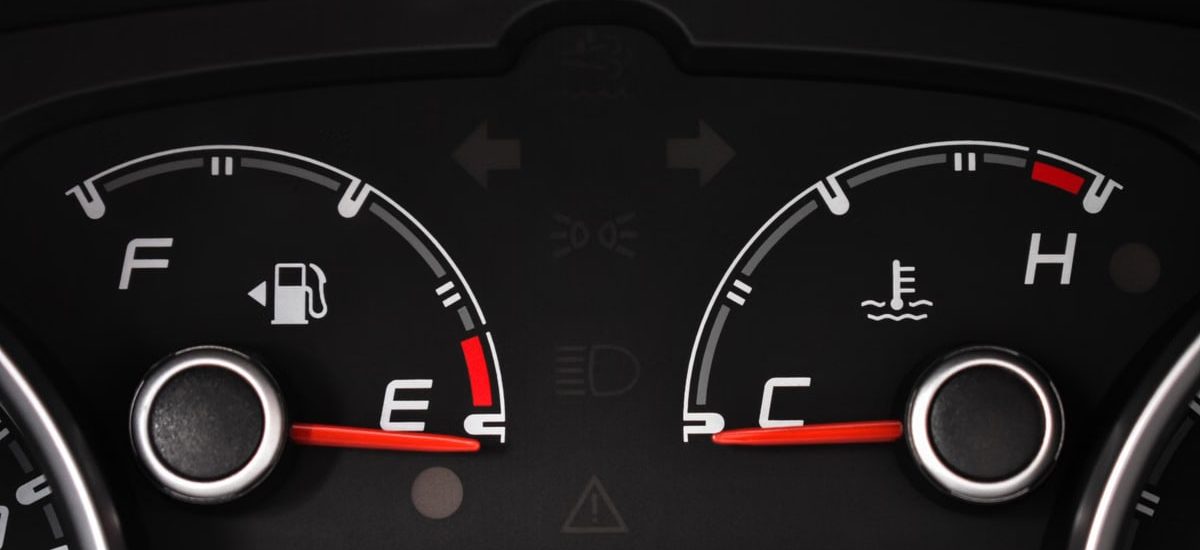 Detailed view of a car's fuel and temperature gauges on dashboard.